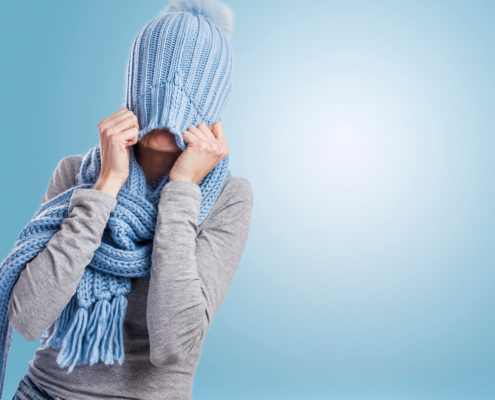 Woman tugging a blue knitted hat over her head