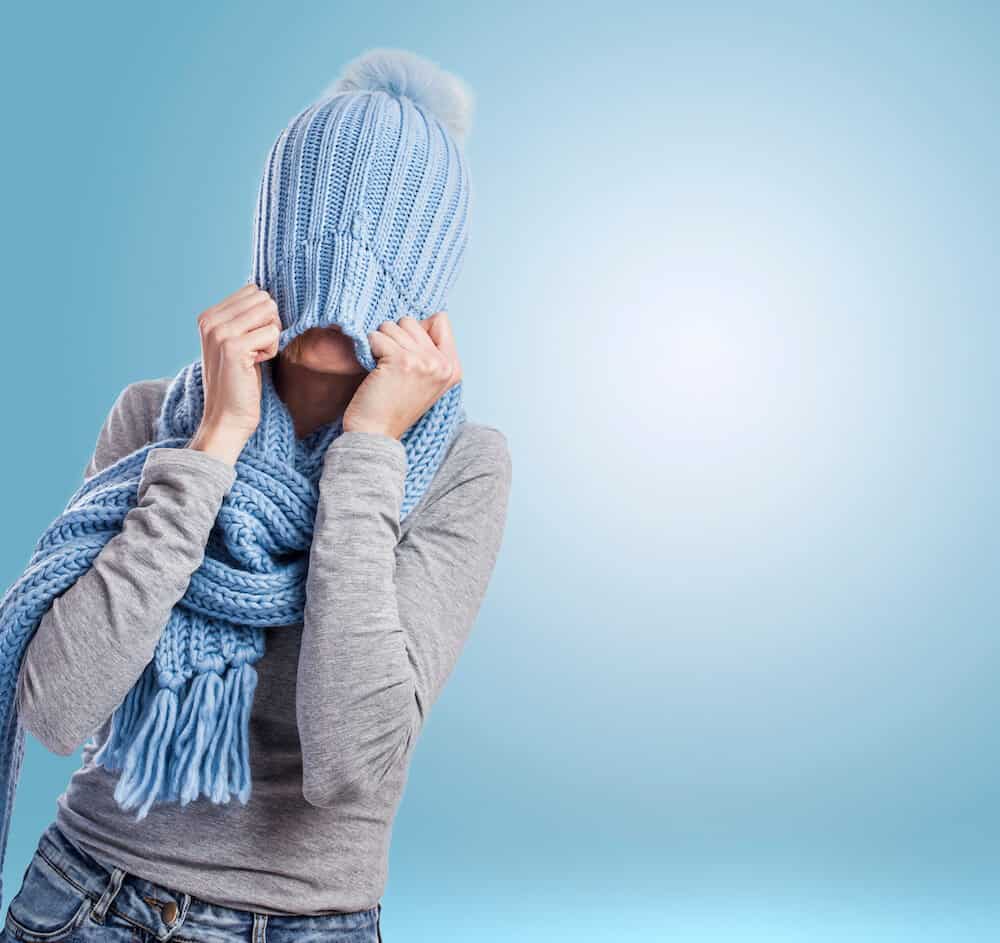 Woman tugging a blue knitted hat over her head