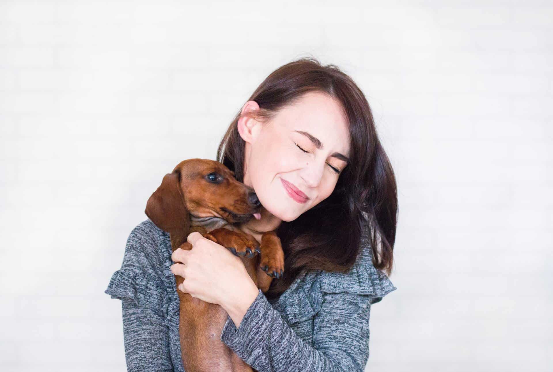 Woman holding a dog that licks her face