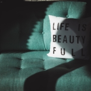 Green sofa with a white pillow holding the text "Life is beautiful"
