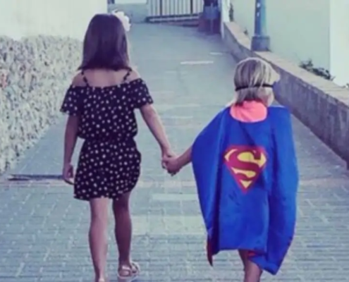 Girl holding hands with child superman