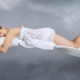 Girl sleeping on flowing white bedsheets