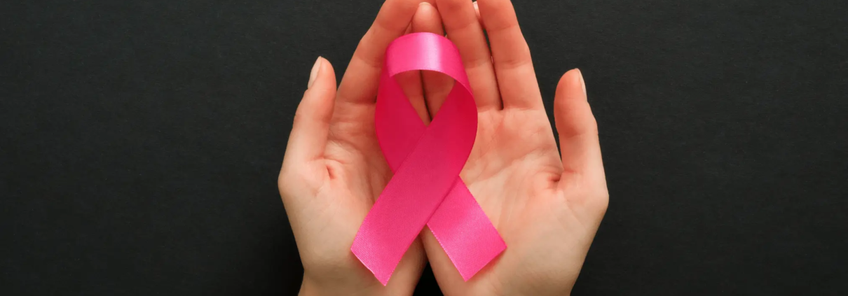Hand holding a pink cancer ribbon