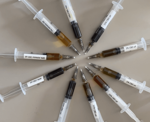 10 syringes with different CBD oil laid out in a circle, demonstrating the colour difference