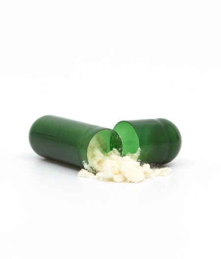 Green CBD capsules open with CBD powder coming out - The Real CBD Brand