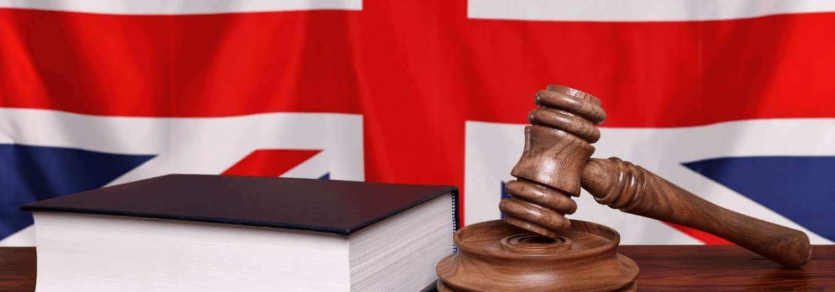 Judge's hammer and a law book in front of the British flag