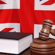 Judge's hammer and a law book in front of the British flag