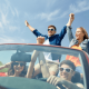 A group of young people driving in a cabriolet having a good time