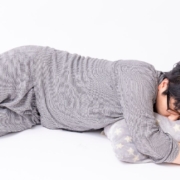 Person sleeping on the floor in grey pyjamas