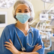 A nurse with a mask on standing in an operating room