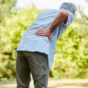 Old man with back pain holding his lower back