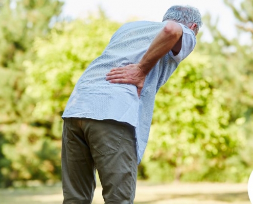 Old man with back pain holding his lower back