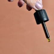 Hand holding dropper with oil drop
