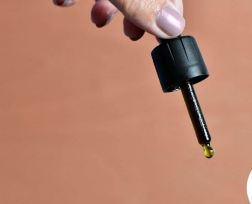 Hand holding dropper with oil drop