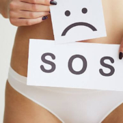 Woman holding SOS sign over her pelvis