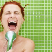 Happy woman singing into the shower head