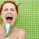 Femme heureuse chantant dans la pomme de douche
