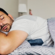 Man sleeping soundly on his stomach in a fresh bed