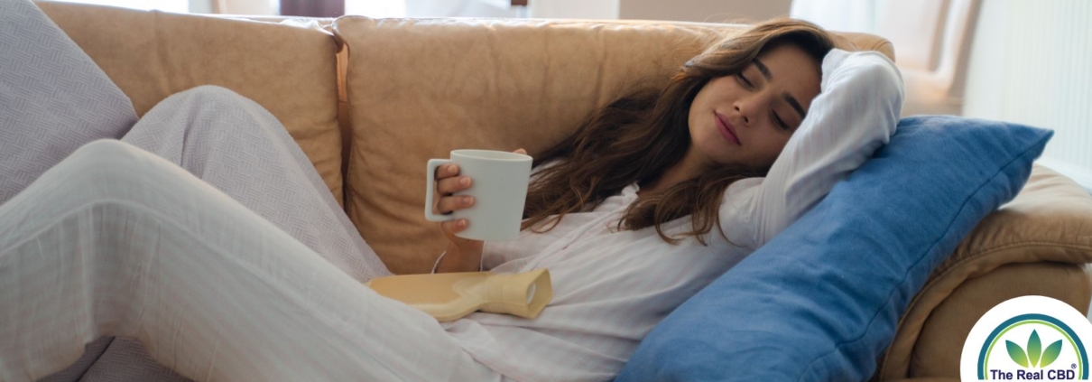 Woman laying on a sofa drinking from a white mug