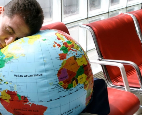 Man sleeping with his head on a globe in an airport