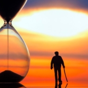 Old man walking next to a time glass
