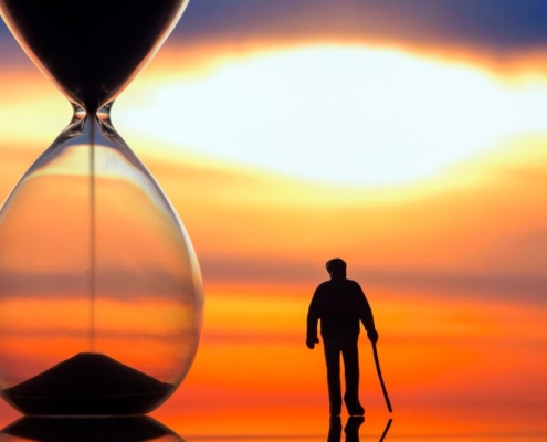 Old man walking next to a time glass