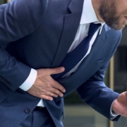 Man with food in hand bending over in pain