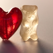 Two white gummy Bears with a red gummy heart in-between