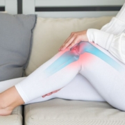Woman sitting on a sofa, holding her knee joint in pain
