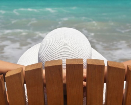 Femme assise sur une chaise de plage au bord de la mer, en train de se détendre