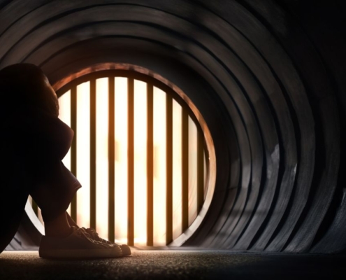 In einem Tunnel sitzende Person mit dem Kopf zwischen den Knien
