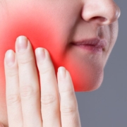 Woman holding cheek in tooth pain
