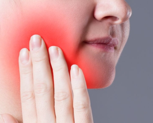 Woman holding cheek in tooth pain
