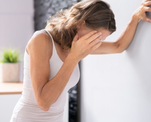 Woman leaning against the wall, touching her head in exhaustion