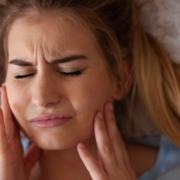 Woman holding her cheeks in pain after teeth grinding