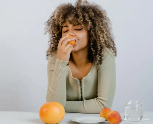Woman enjoying a peach at a dinner table