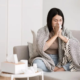 Woman with a clod on the sofa while blowing her nose