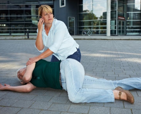 Woman calling for help for a person on the ground having a seizuer
