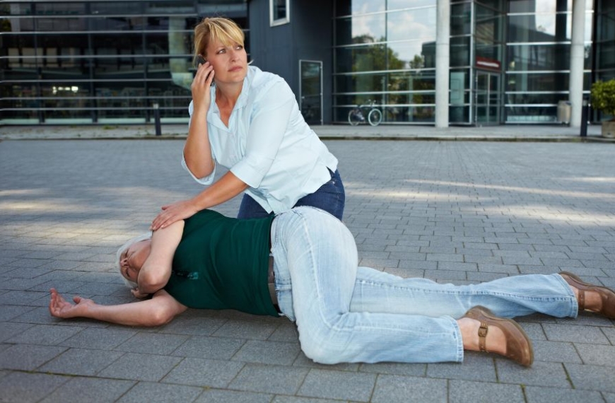 Frau ruft um Hilfe für eine Person am Boden, die einen Krampfanfall hat