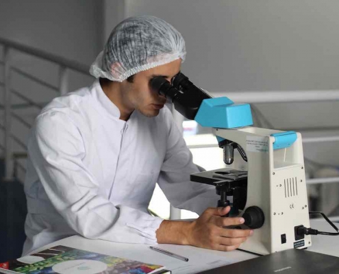 Científico en el laboratorio mirando por el microscopio