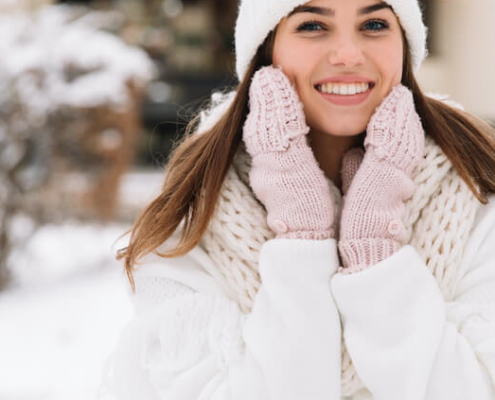 Mujer en la nieve sonriendo mientras se sujeta la cara