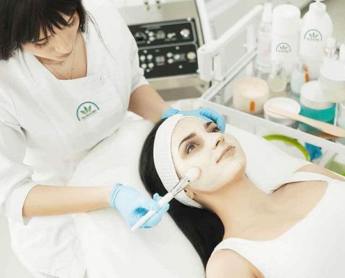 Esteticista tratando a una mujer con una mascarilla facial