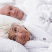Una pareja de ancianos en la cama. Uno durmiendo, otro despierto