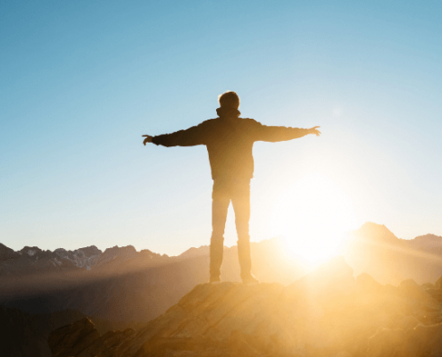 Hombre en la cima de una montaña al amanecer