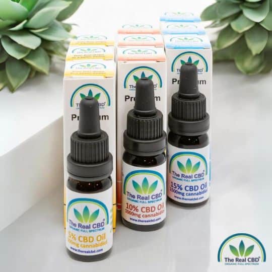 3 botellas de aceite de CBD sobre mesa con plantas