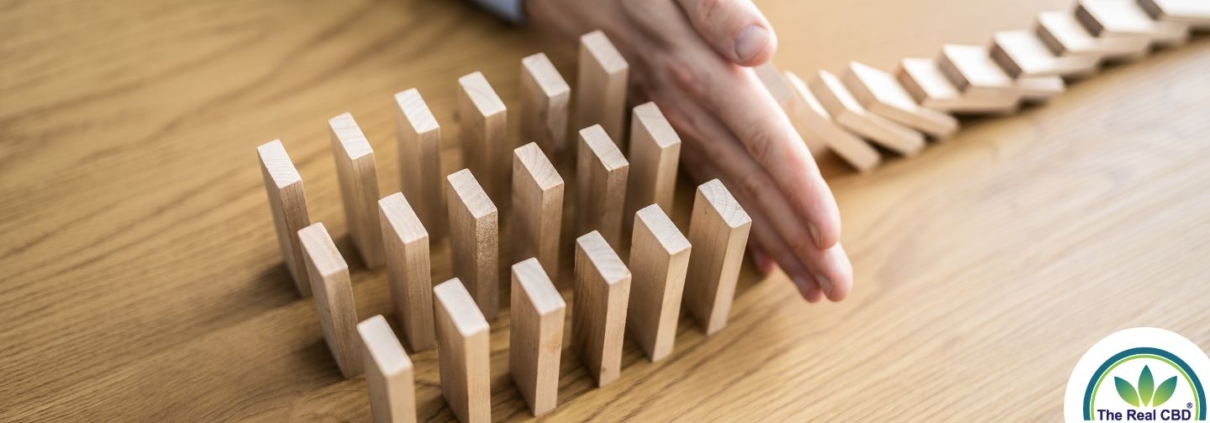 Hand, die verhindert, dass Holzziegel wie Dominosteine fallen