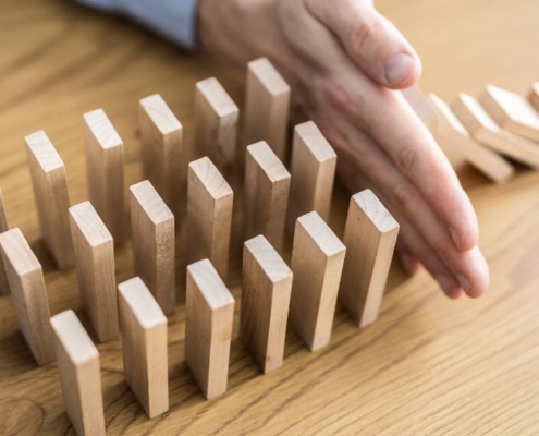 Main empêchant les briques de bois de tomber comme des dominos