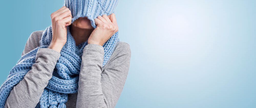 Woman tugging a blue knitted hat over her head