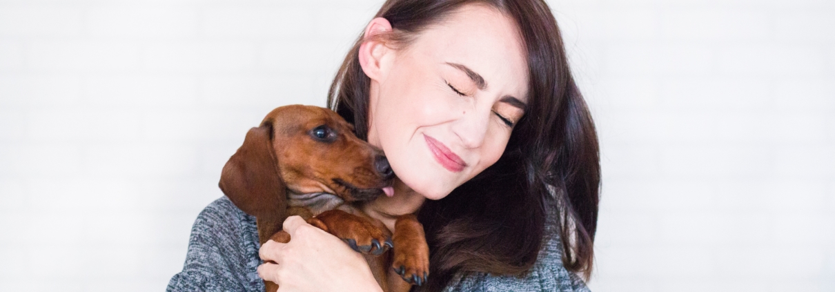 Woman holding a dog that licks her face