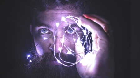 Man holding fairy lights infront of his face